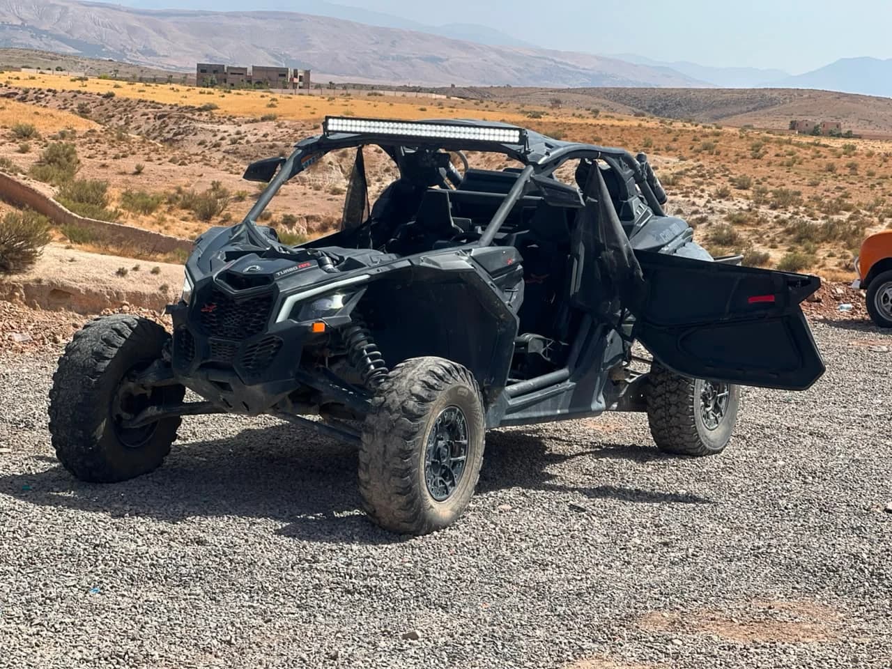 The rental business's own Can-Am Maverick X3 off-road buggy, parked in the Agafay Desert with hills in the background