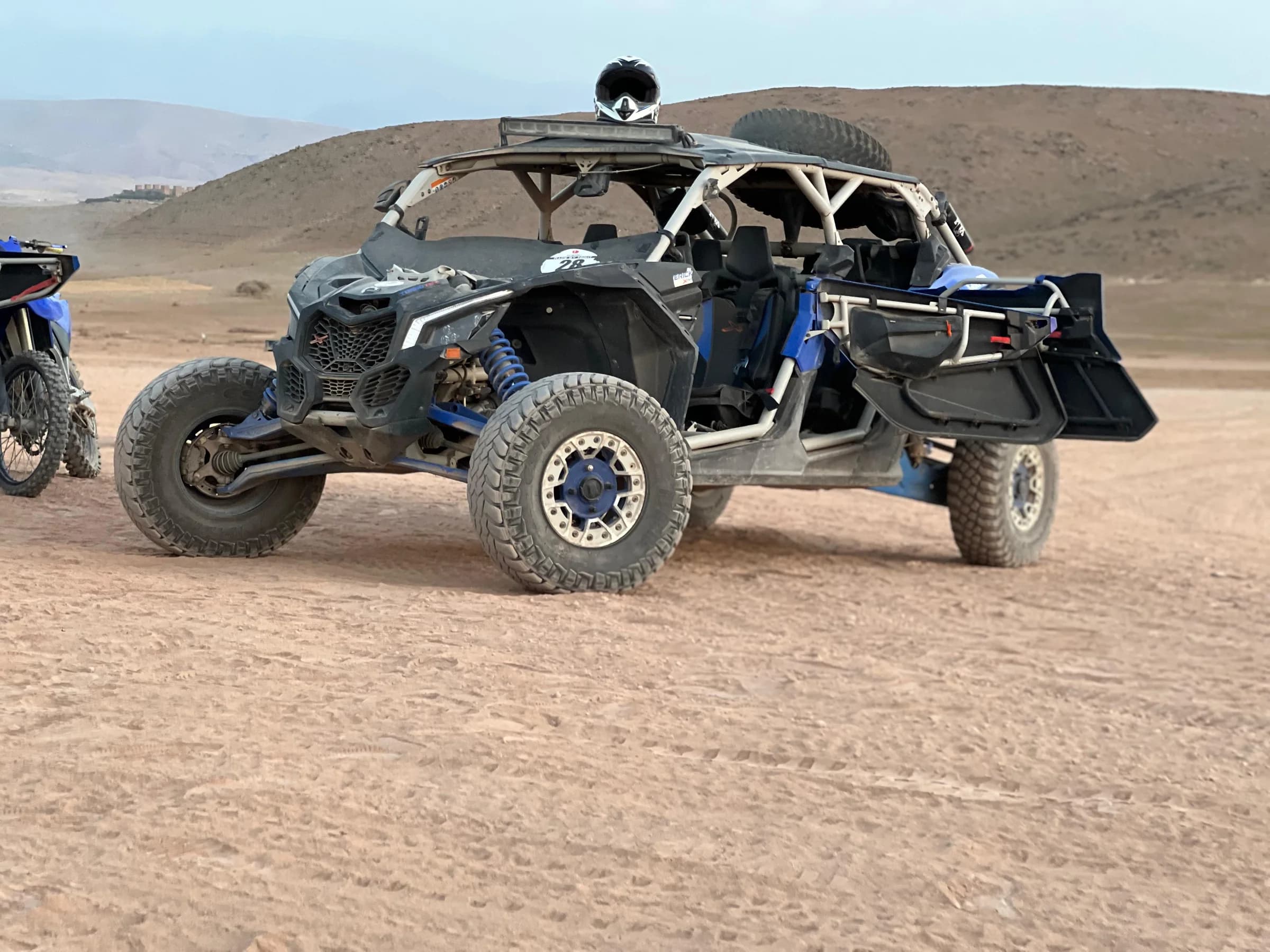 An off-road buggy driving across a desert dune