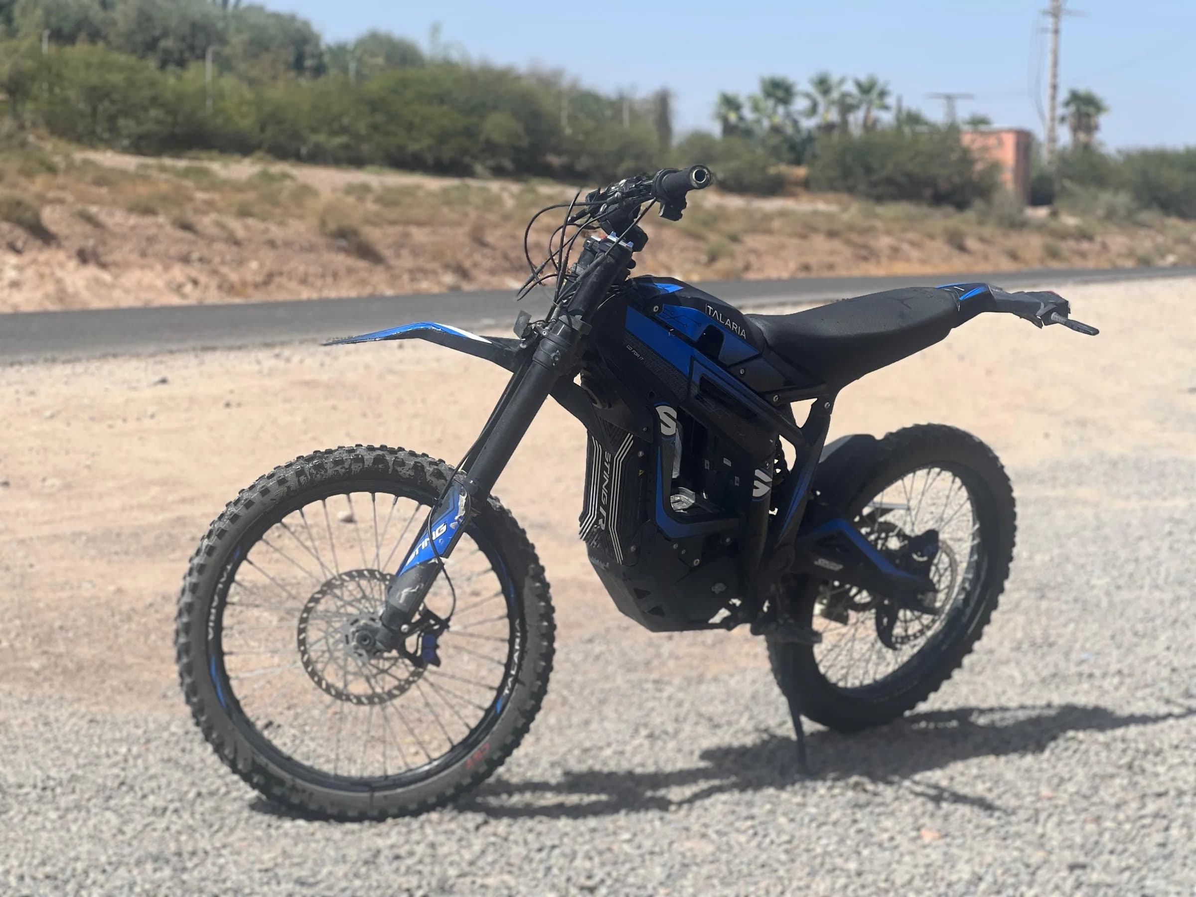 A blue dirt bike parked beside a road