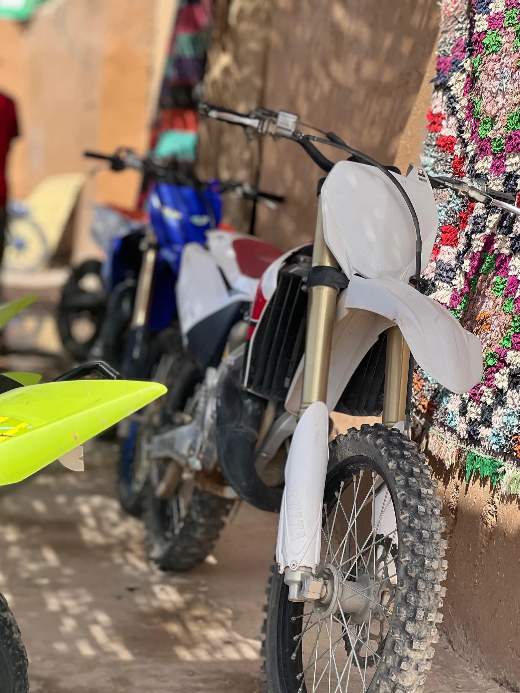Two dirt bikes parked against a decorated wall