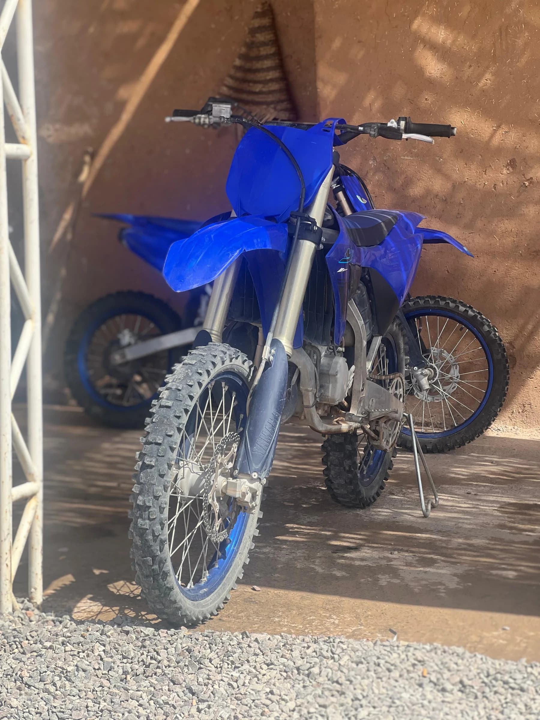 A blue dirt bike parked against a shop wall