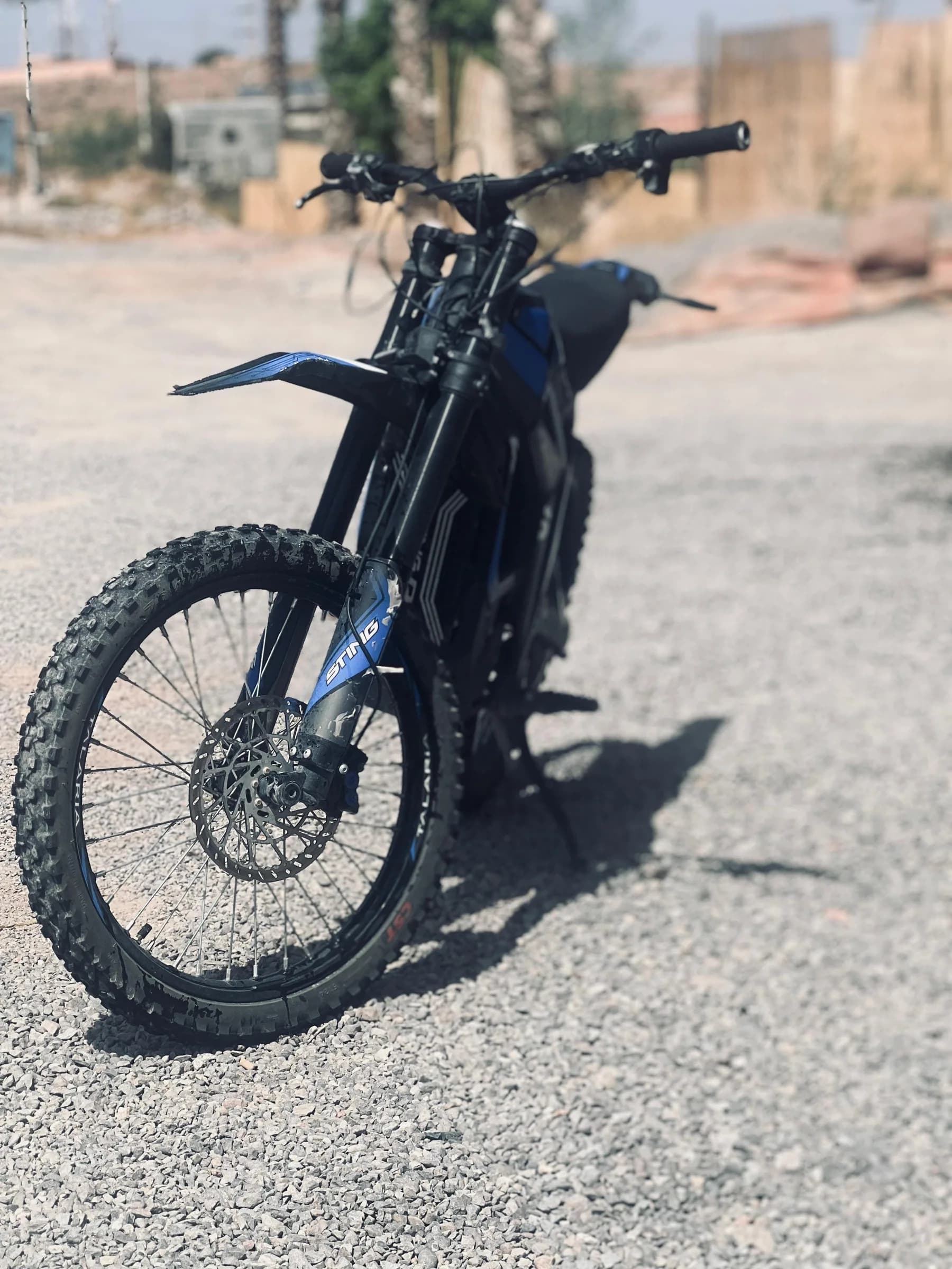 A black electric dirt bike parked with a desert view behind it