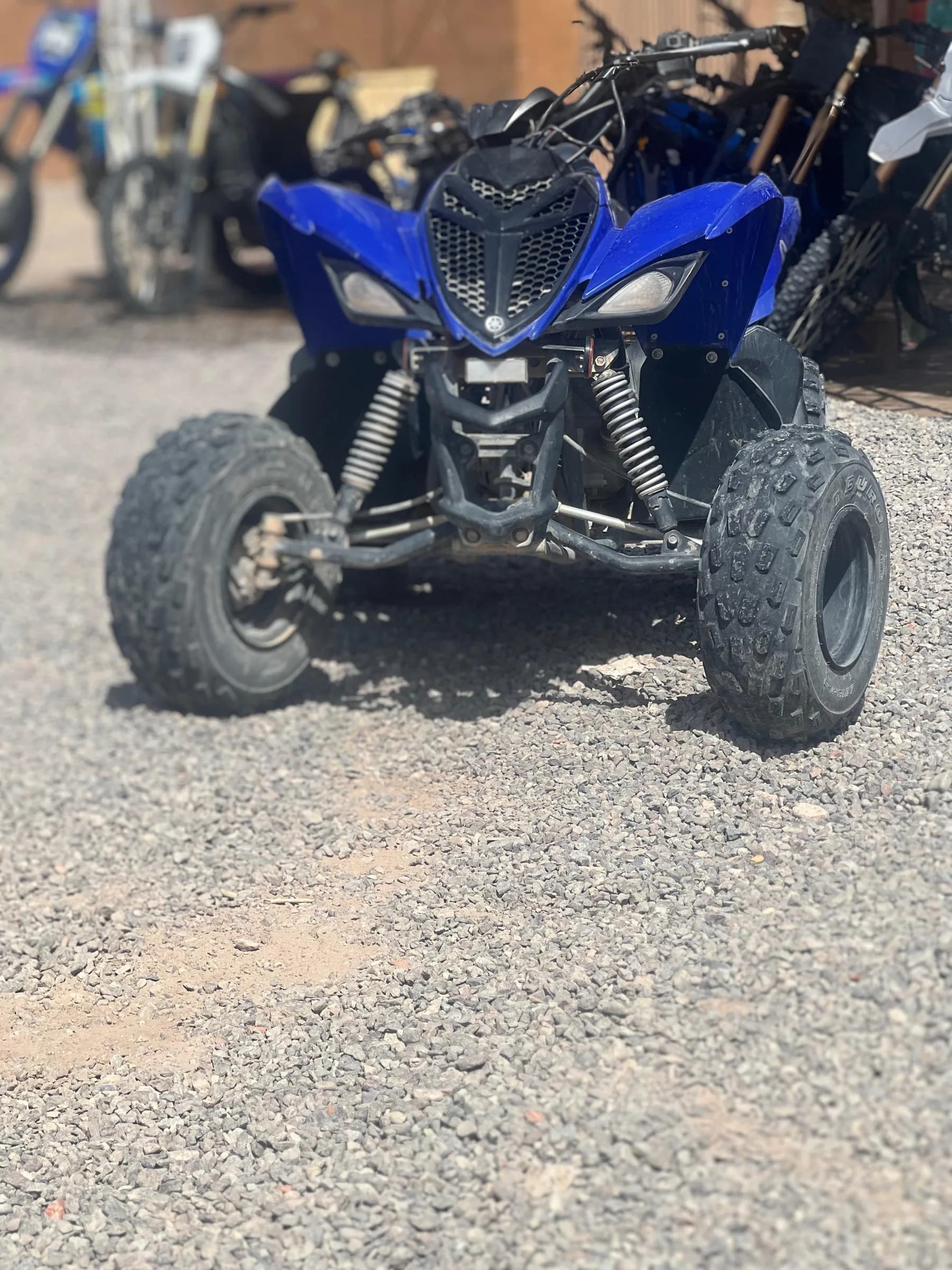 Front view of a blue quad bike parked at a rental yard