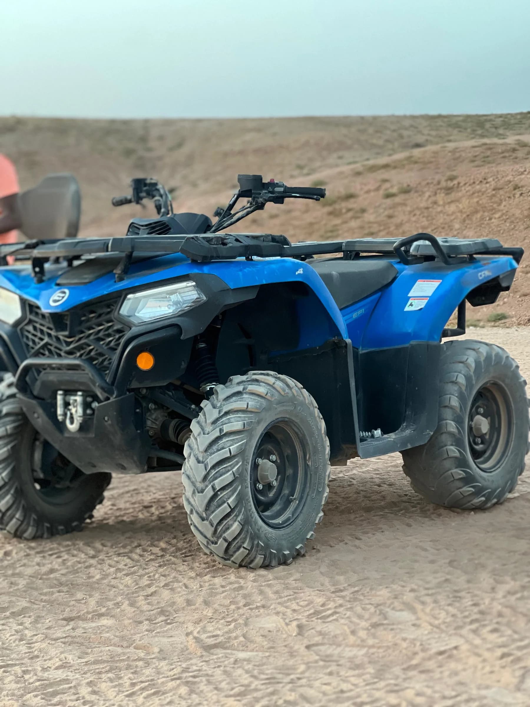 A blue quad bike parked in a gravel yard