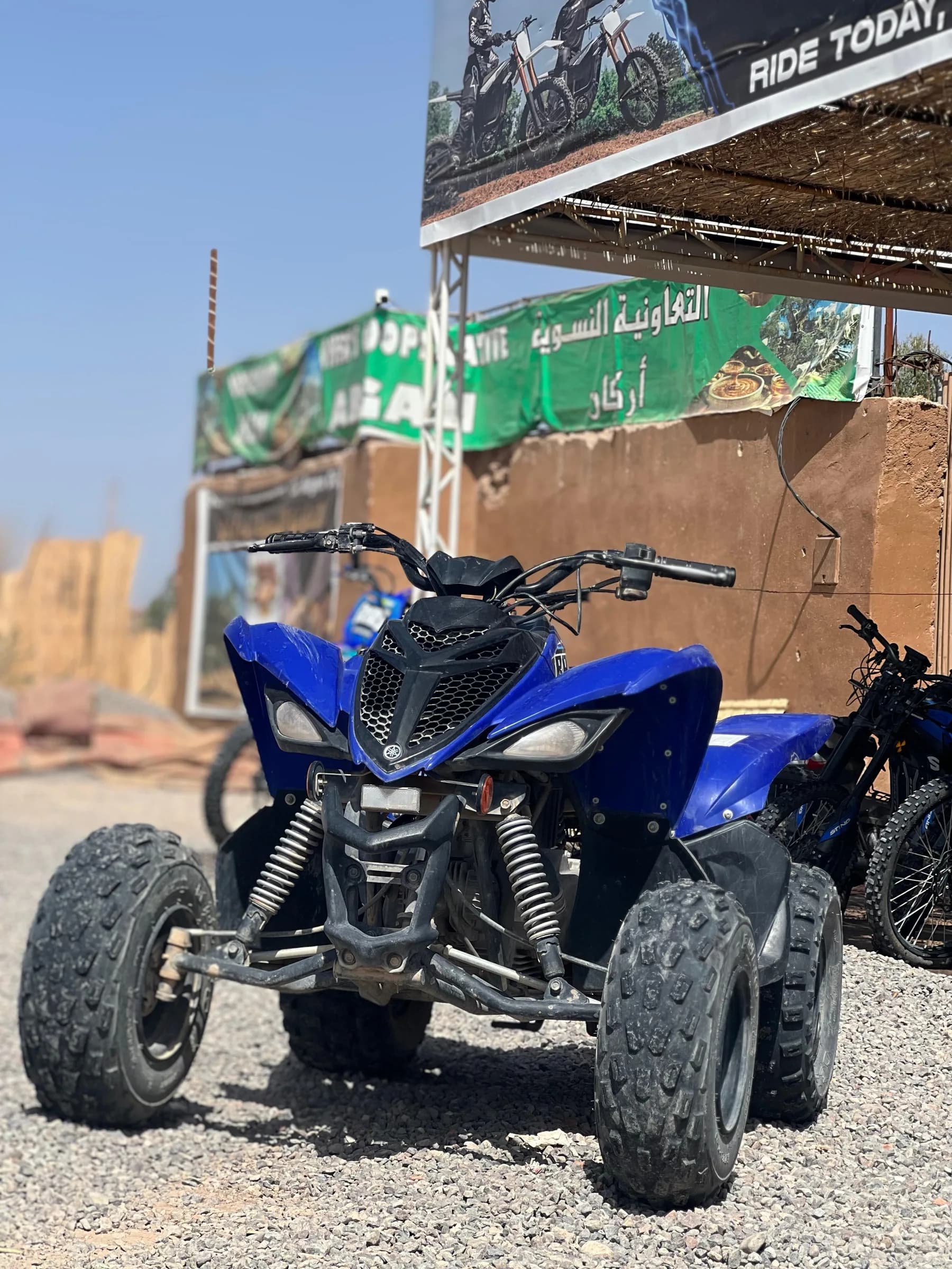 A blue quad bike parked under the "Ride Today" shop sign
