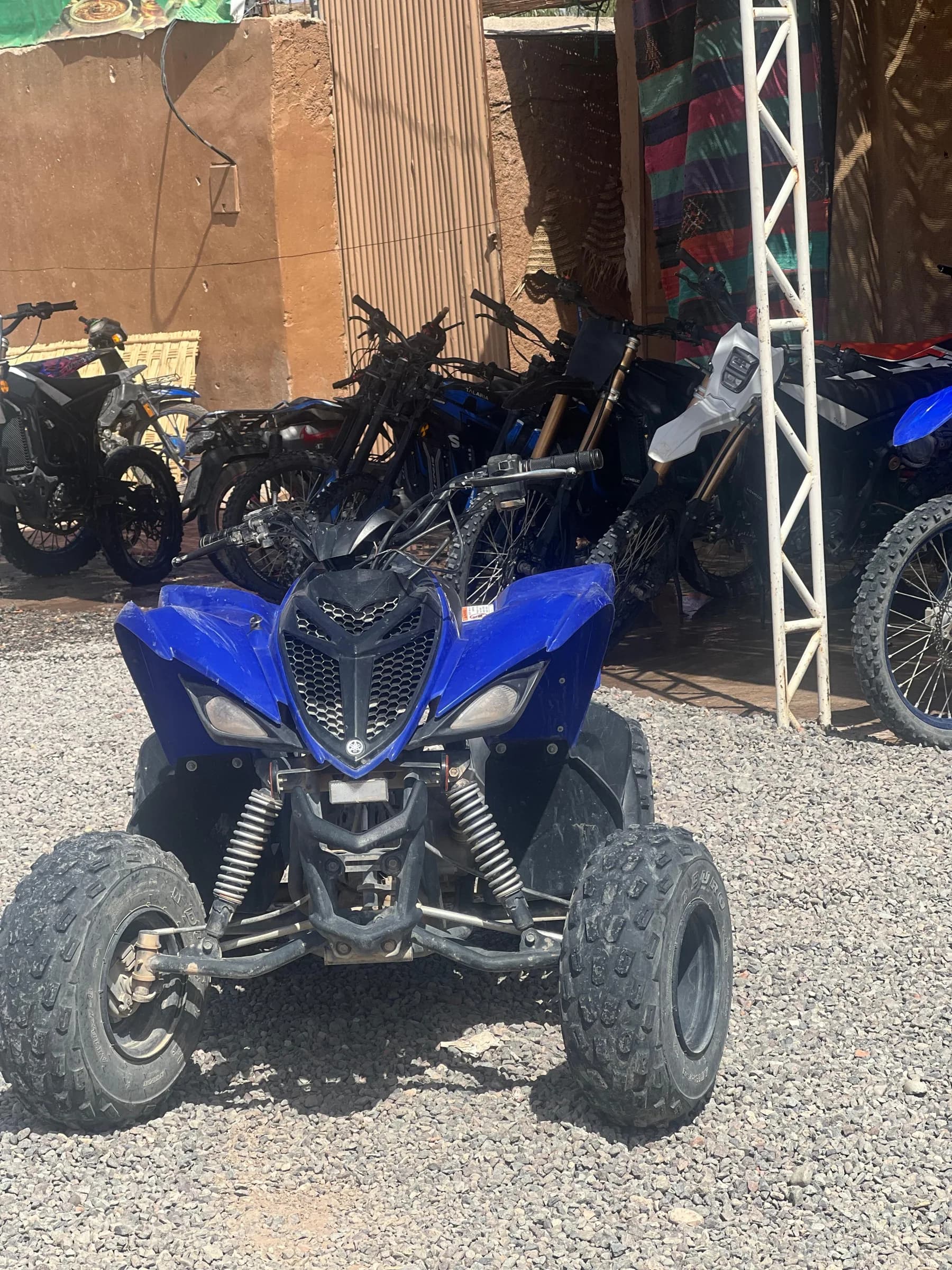 A blue quad bike parked in front of a row of motorcycles