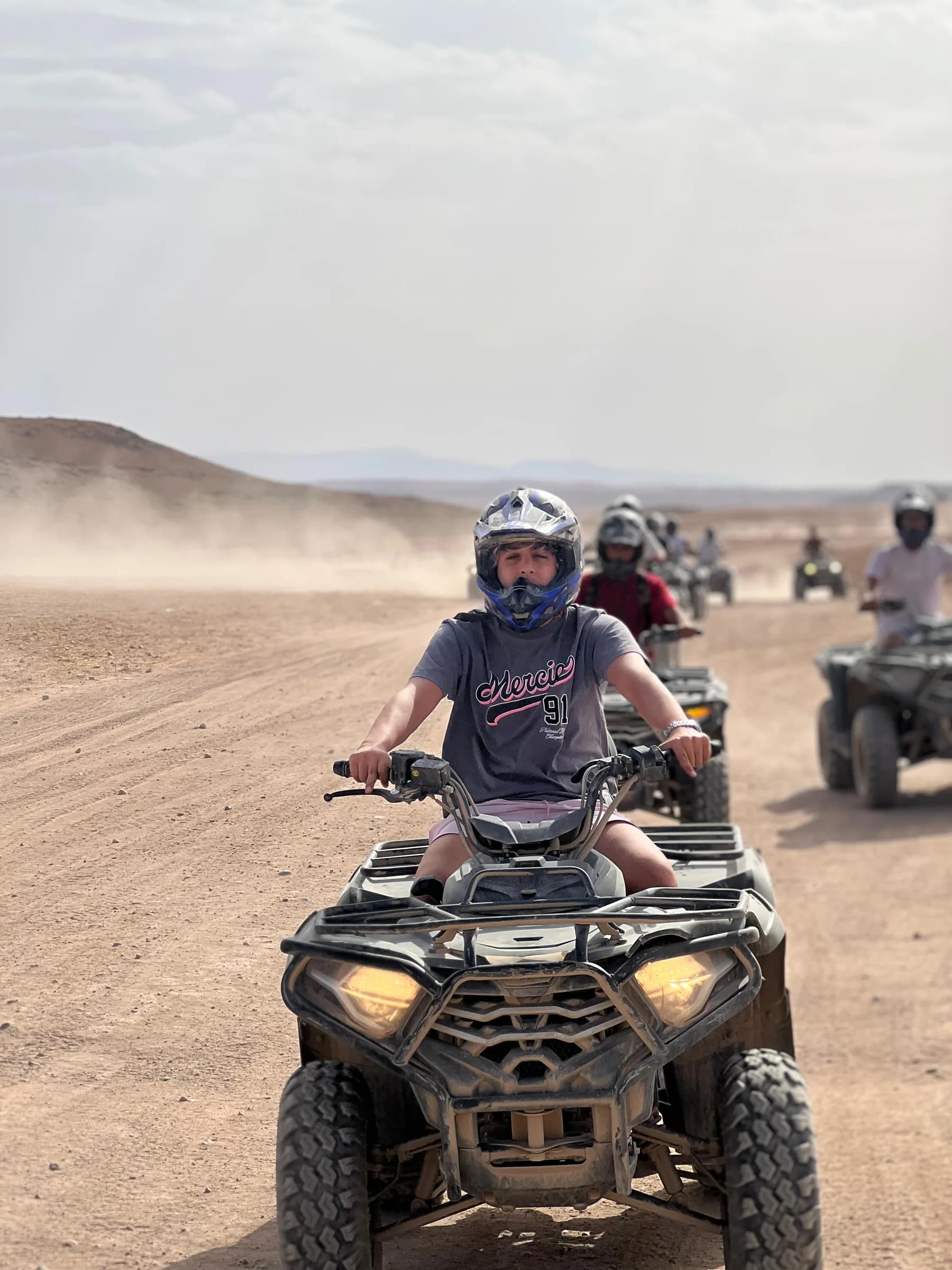 A rider on a quad bike leading a group along a desert trail