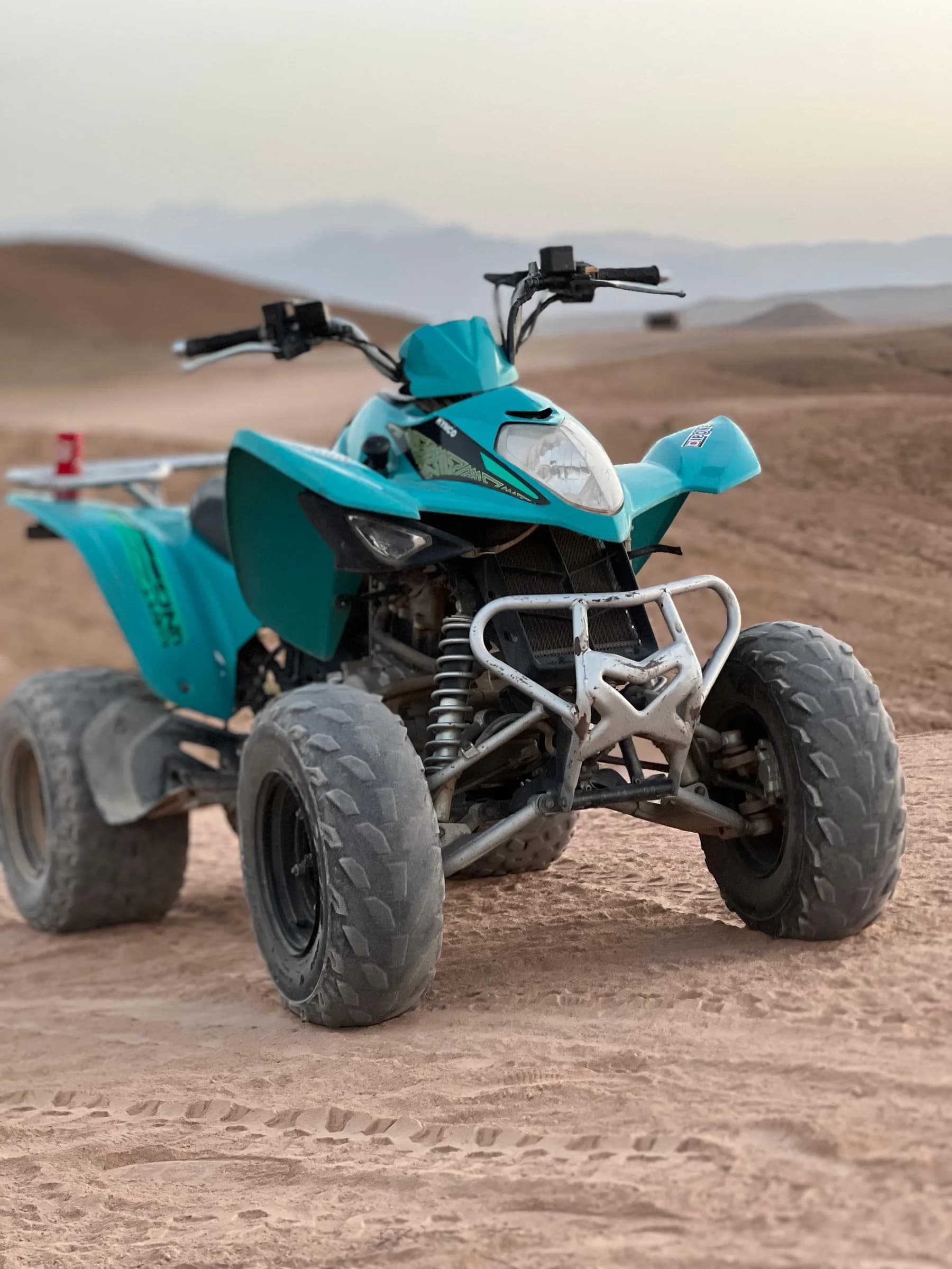 Close view of a teal quad bike with a desert backdrop