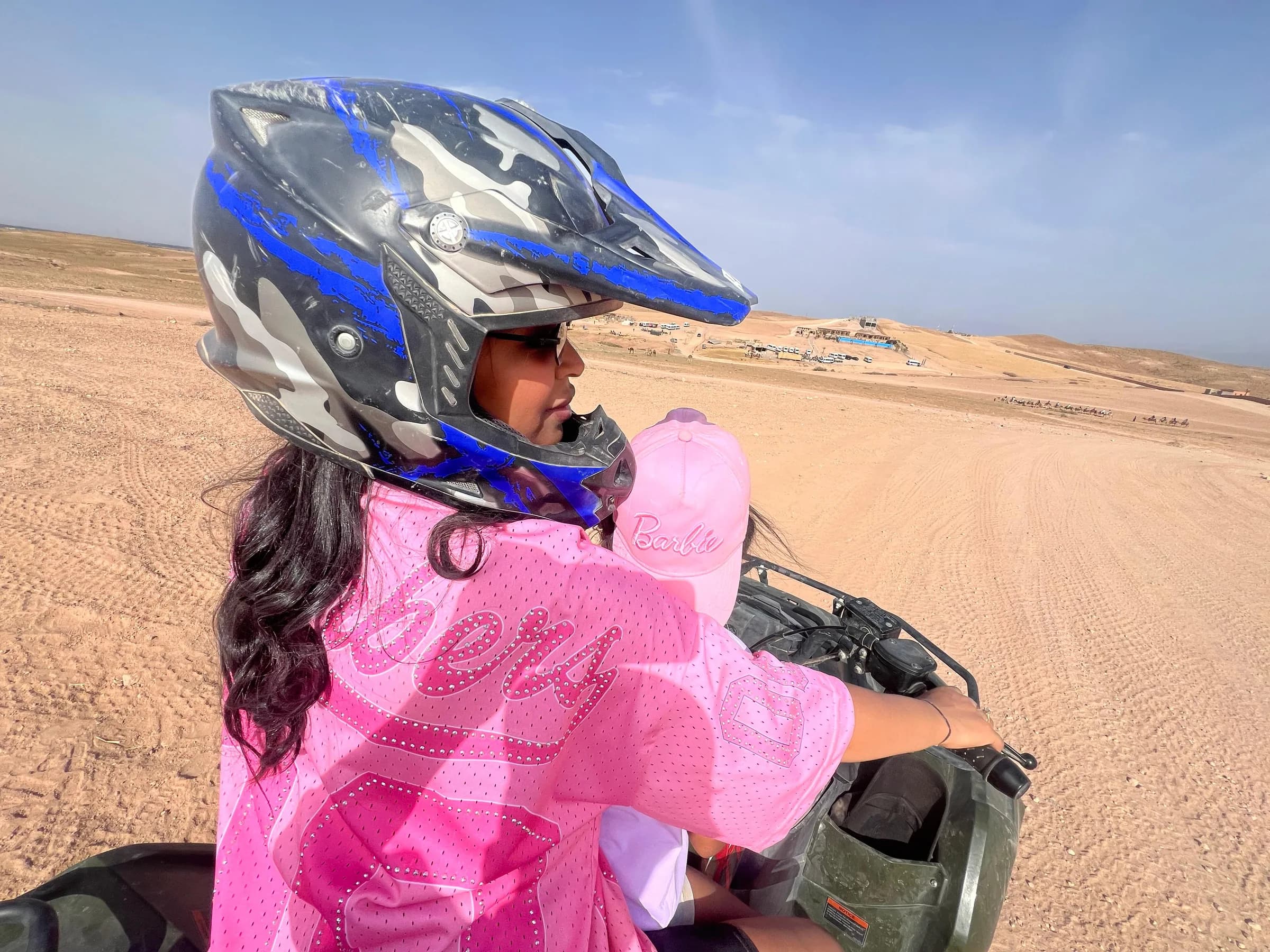 A girl wearing a helmet and a pink jacket in the desert